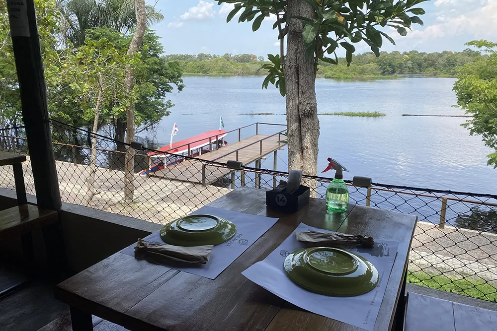 Mesa posta com pratos verdes e vista do rio e do píer