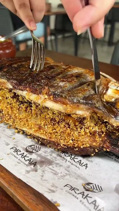 Peixe assado com crosta de farofa sendo servido