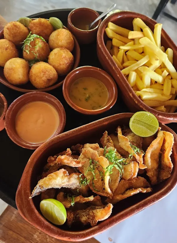 Entradas: bolinhos fritos, iscas de peixe com limão, batata frita e molhos